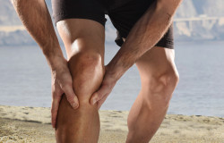 Young Sport Man With Athletic Legs Holding Knee In Pain Sufferin