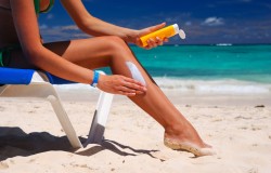 Tan woman applying sun protection lotion