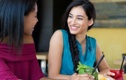 Closeup shot of smiling young woman holding cocktail. Two female