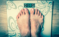 Woman's feet on a scale with word HELP! - obesity concept - retro style